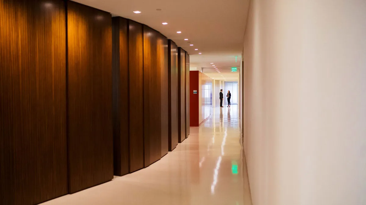 A hallway with dark wood walls and people in the distance