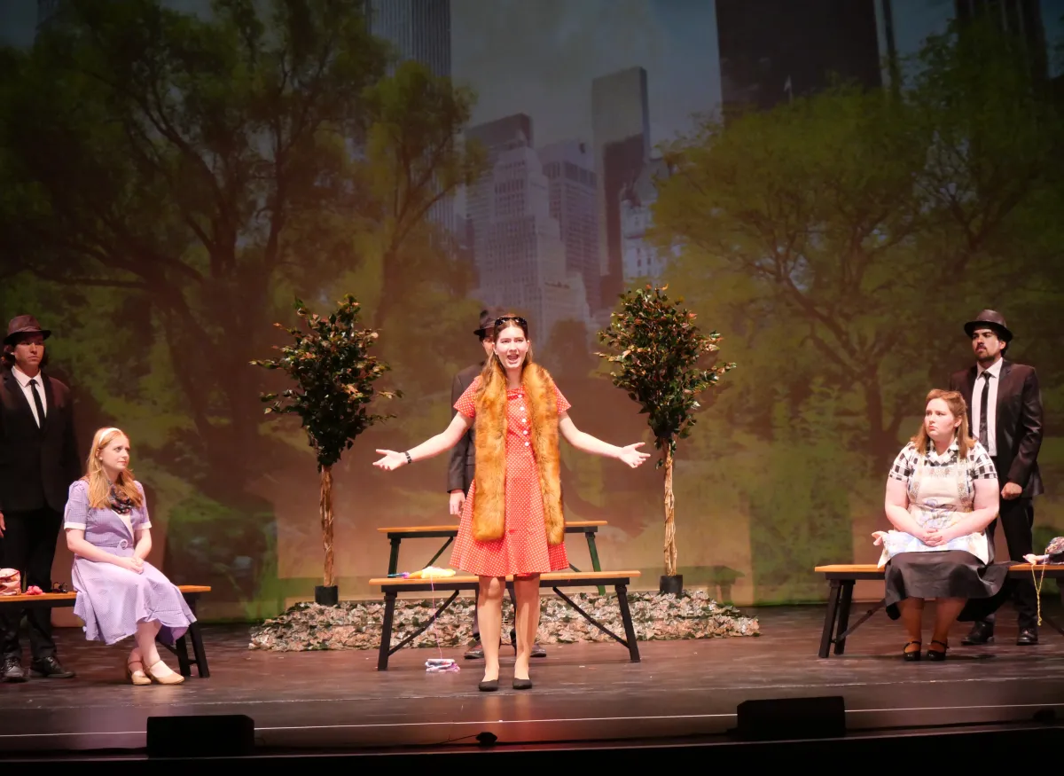 A theatrical scene shows several performers onstage