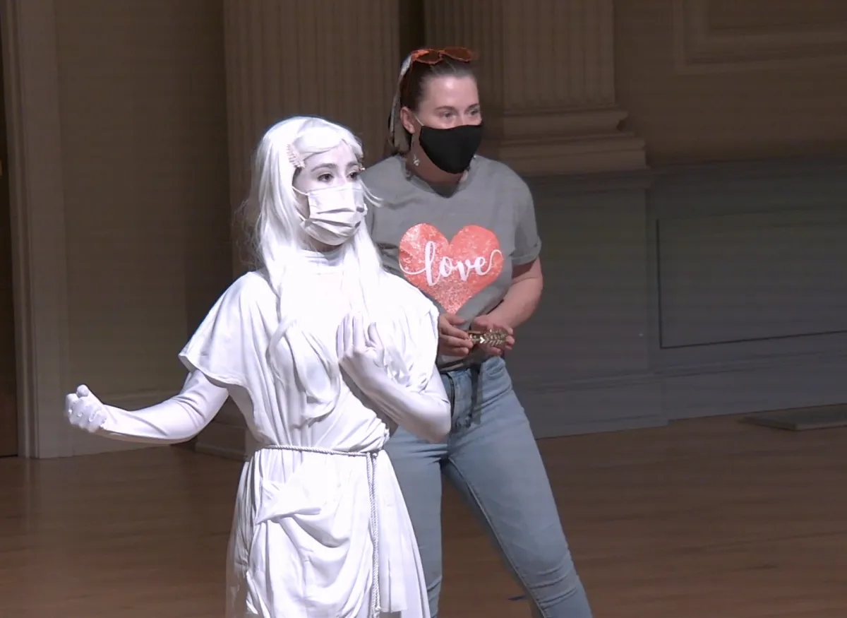 A theatrical scene shows performers onstage