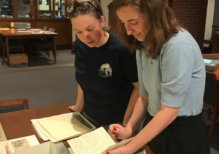 An alum and student examining Civil War Era letters at a research table in Special Collections