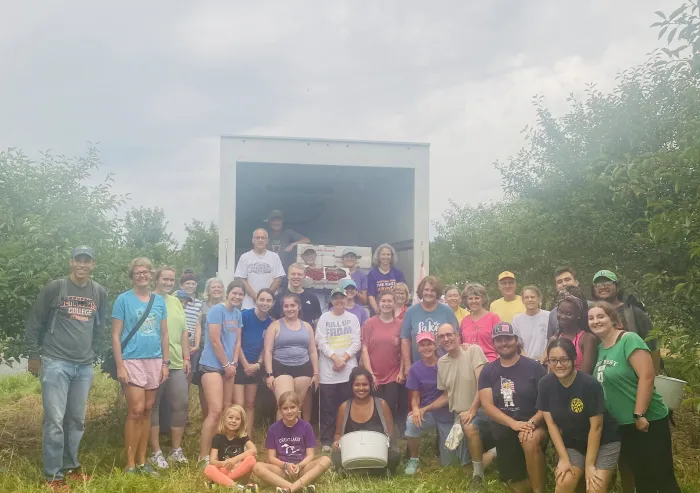 A large group of people standing in front of a produce truck.