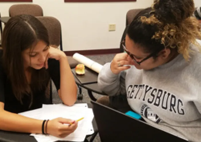 A student tutors a young child.