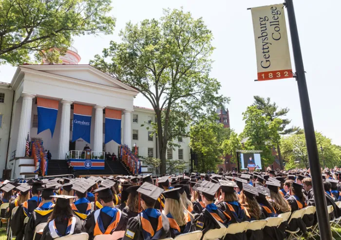 Graduates attend an outdoor commencement ceremony on campus.