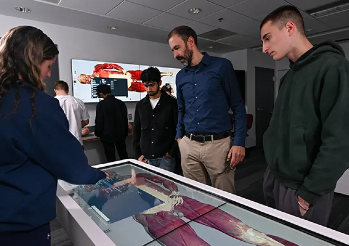 Students examine an anatomical model with an instructor.