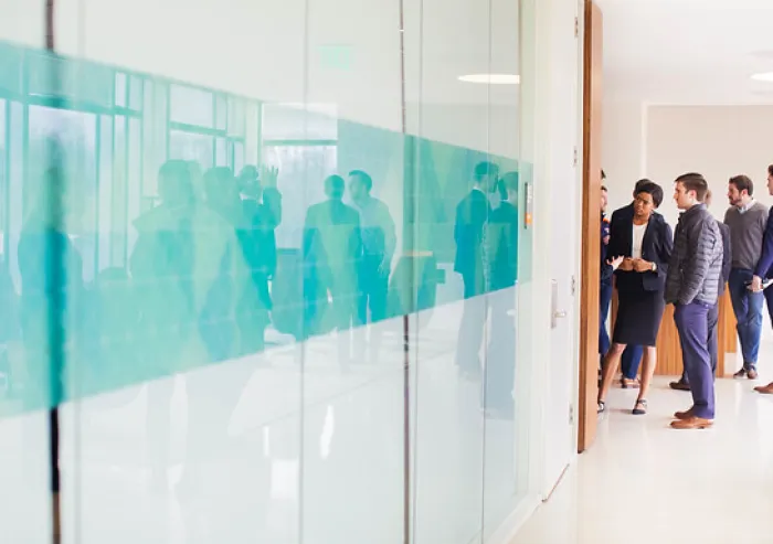 Professionals walk through a bright office hallway.