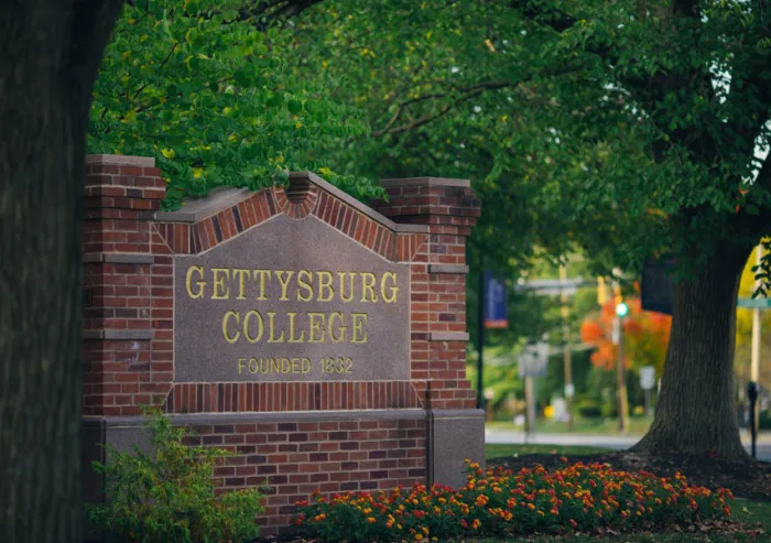 Gettysburg College entrance sign surrounded by flowers.