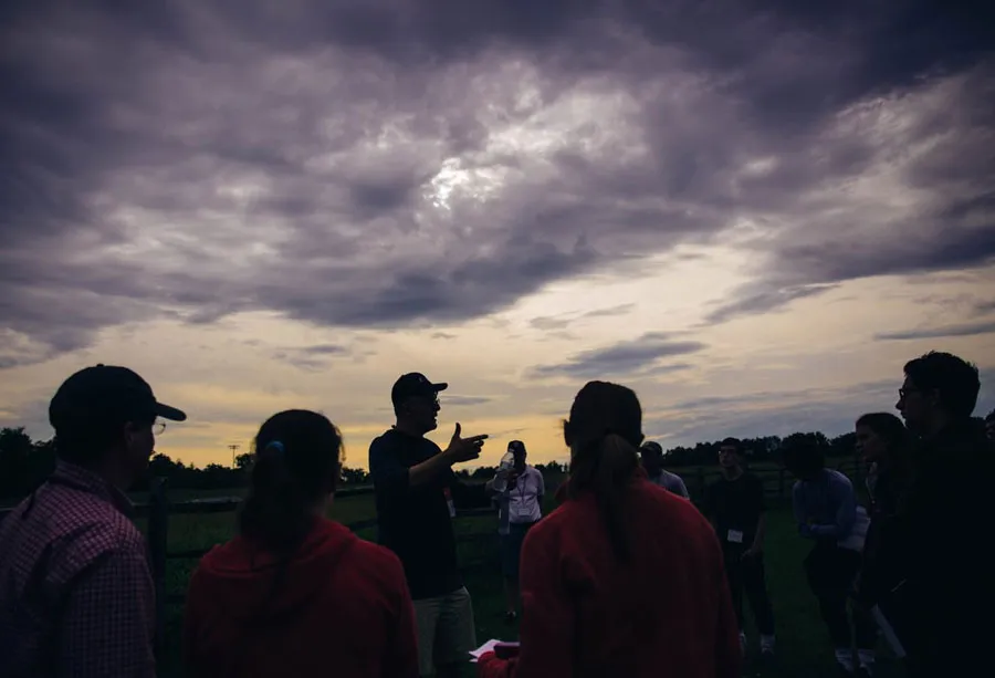 guide speaks to group at dusk on battlefield