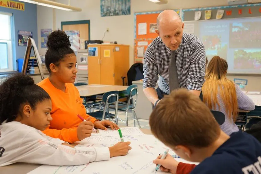 teacher watches young students at work in classroom