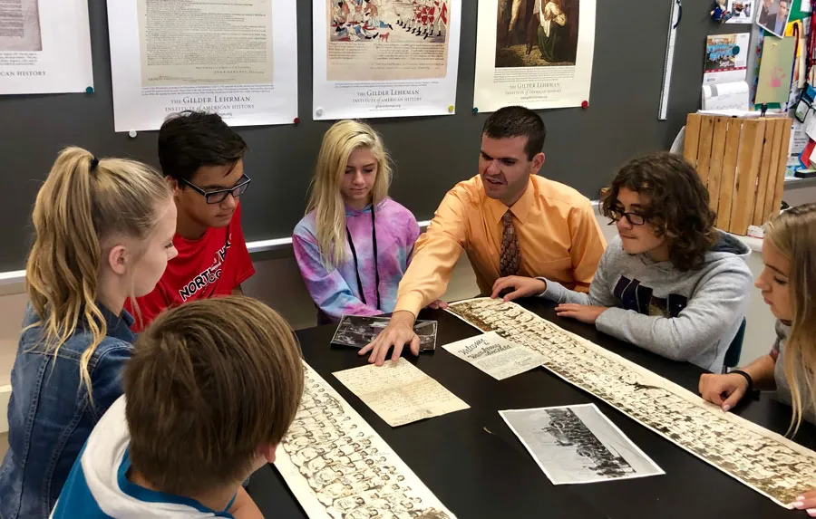 archivist shows young students historical photos at table
