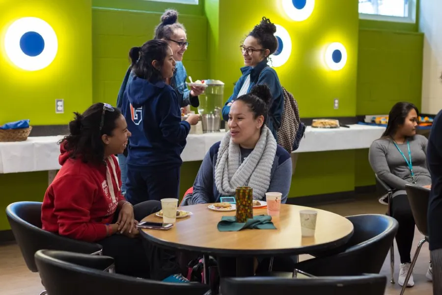 female students laugh and converse at table at reception