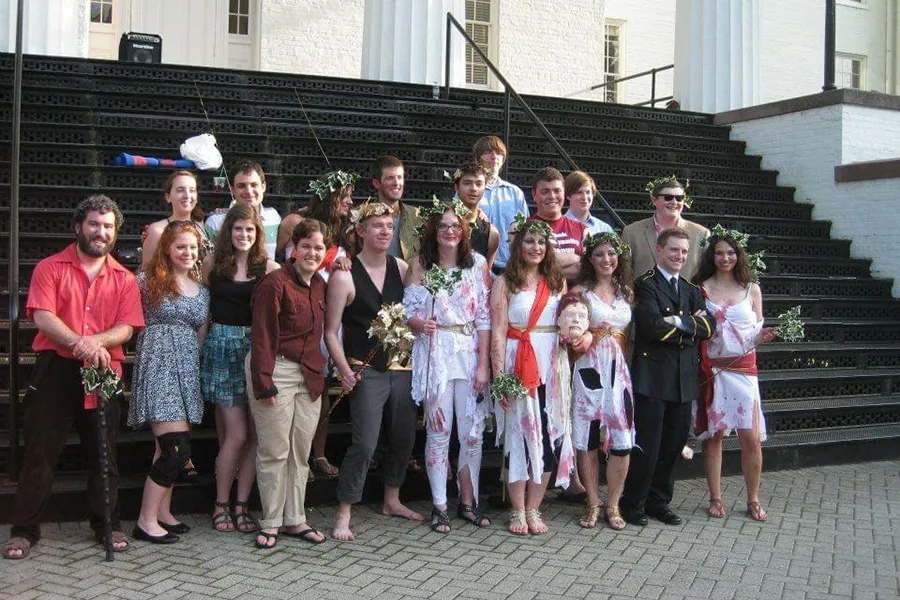 group of students pose in front of portico stairs, some with ivy crowns