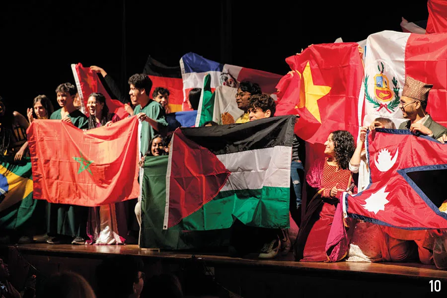 international students on stage hold up all their different national flags
