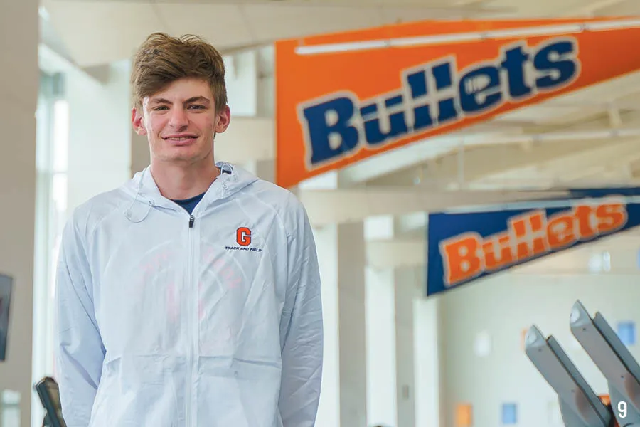 male track and field student-athlete smiles in front of Bullets banners
