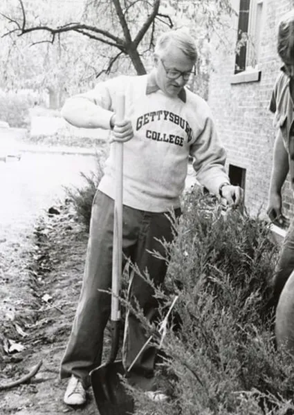 President Charles Glassick planting a shrub