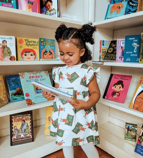 child smiles and looks at books