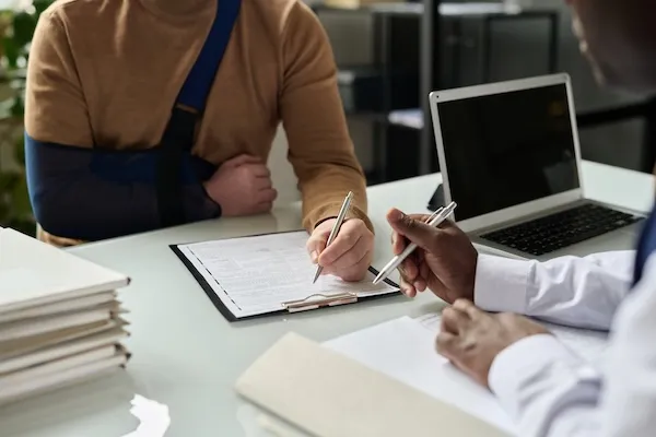 stock image of student in sling filling out paperwork