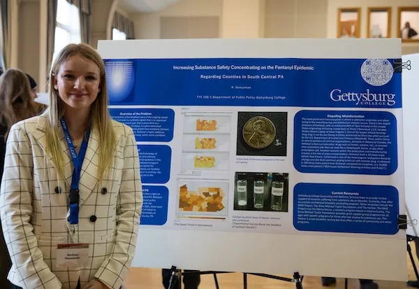 female student smiles in front of research poster
