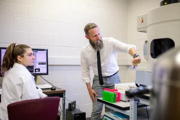 professor gestures at physics machinery