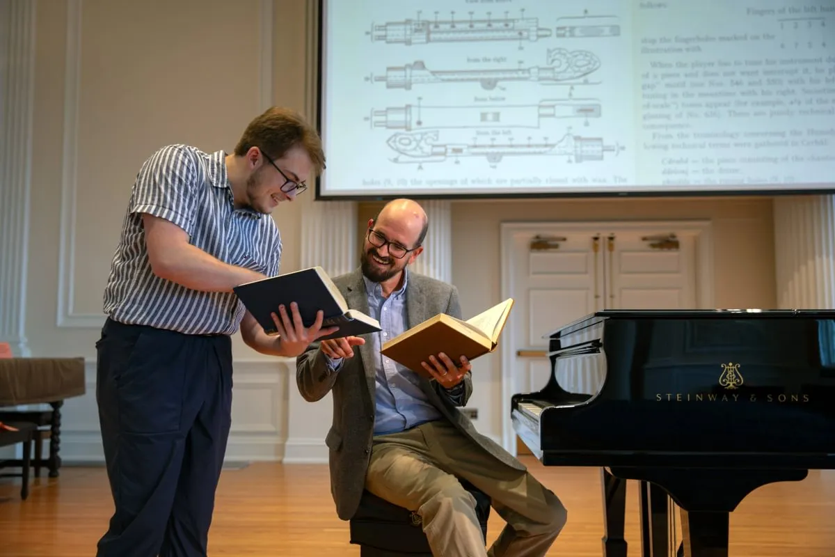 music student and prof smile as they look at book together