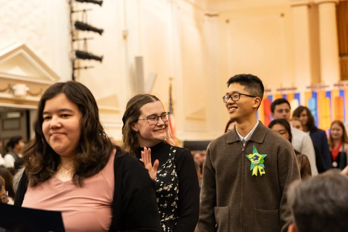 students process and smile at guests