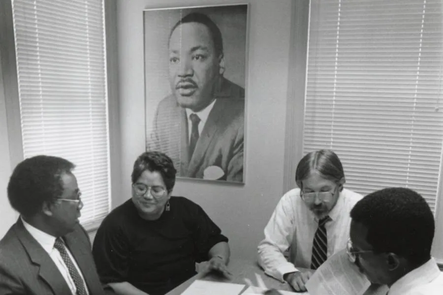 Group photo of the African American Studies Committee in the 1980s featuring Prof. Emeritus Frank Chiteji, Prof. Leticia Diaz, Prof. Michael McTighe, and Prof. Kelfala Kallon standing together.
