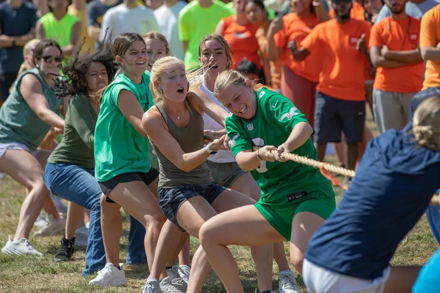 Students participating in a tug of war, pulling on a rope together during an outdoor activity.