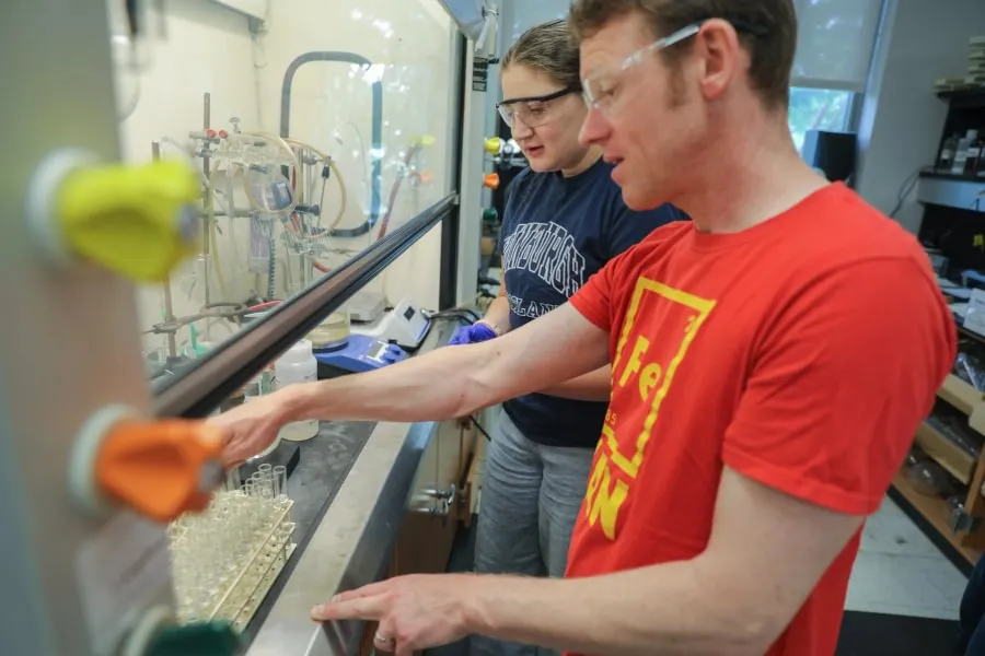 Chemistry and Biochemistry Prof. Timothy Funk ’00 works inside his lab with a student