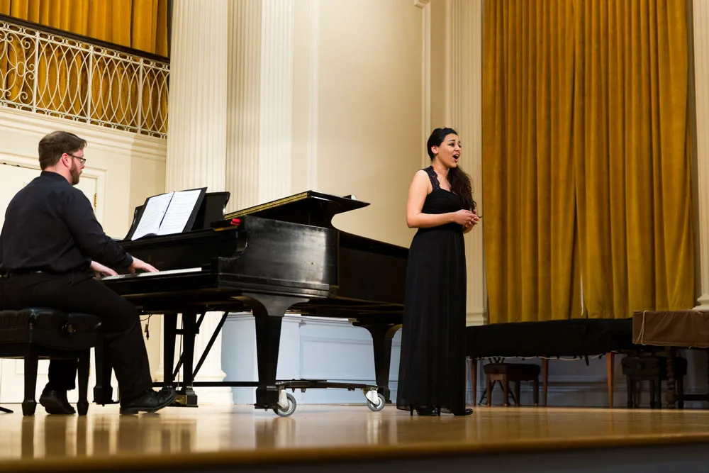 Singer performs with a pianist onstage.