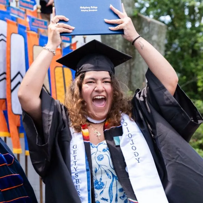 A student holding up her degree