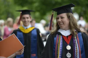 A graduate smiles while receiving the degree 