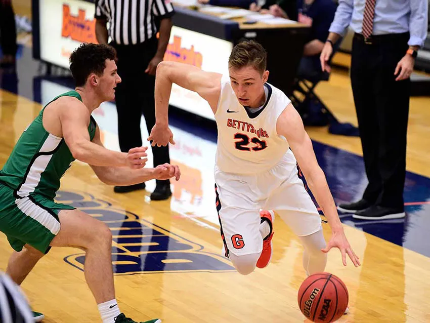 A Gettysburg College basketball player drives to the basket.