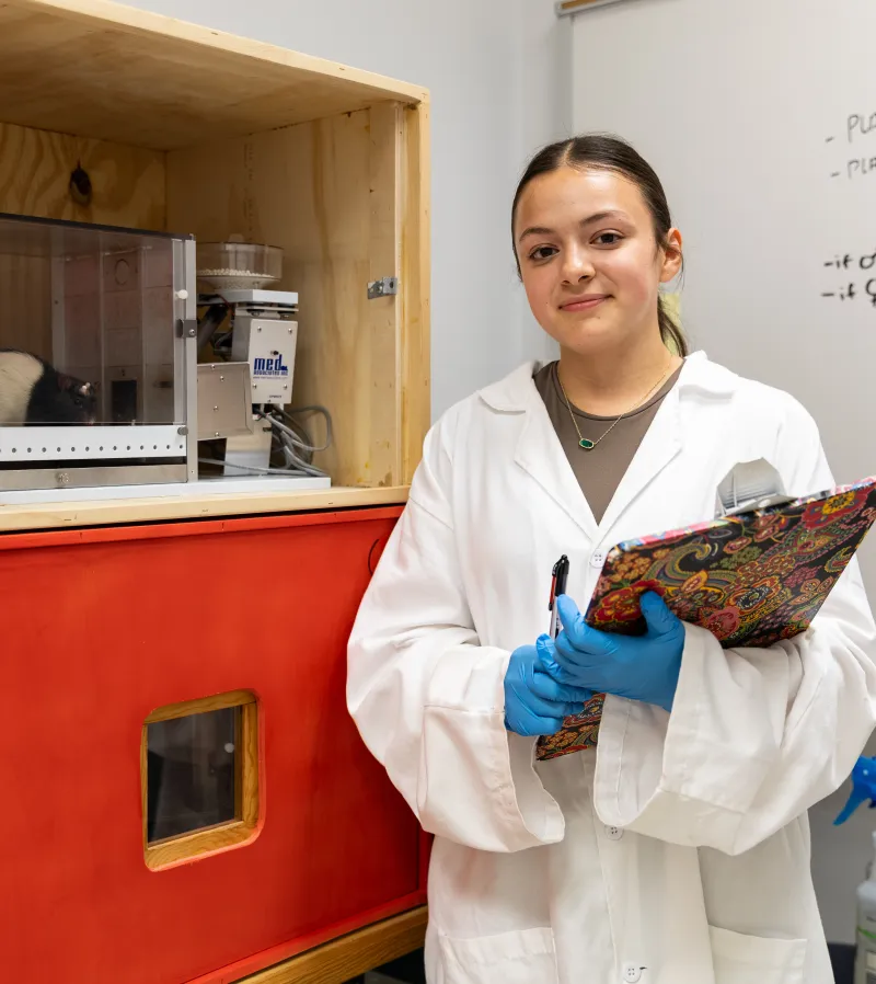 Marina Lomelli standing in classroom in lab coat with clipboard