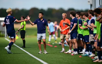 Men's soccer head coach Dan Malone gives a high-five to a player.