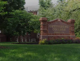 Gettysburg College entrance sign in a shaded campus landscape.