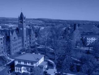 Blue-tinted aerial view of a campus clock tower and buildings.