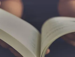 A photo of of a pair of hands holding an open book.