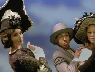 Three performers on-stage during a theatre production.