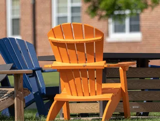 Colorful Adirondack chairs arranged around a table on a lawn