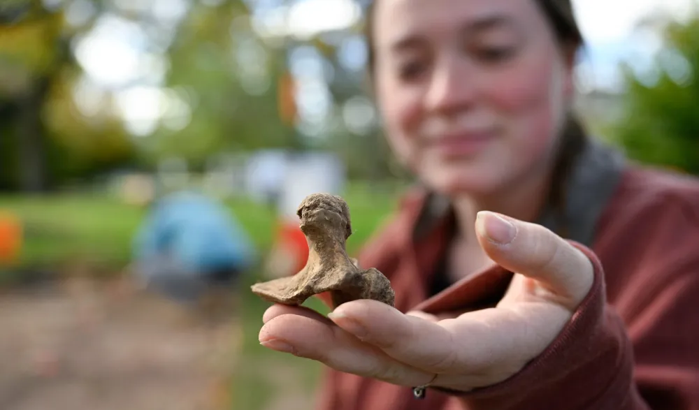 student holds up dig site finding