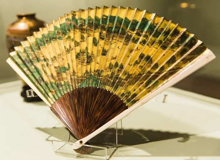 A photo of a handheld fan with an artistic design.