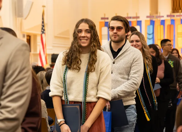 Graduates walk in procession through a hall.