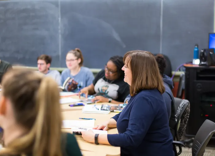 Prof leads class sitting with desks in big circle
