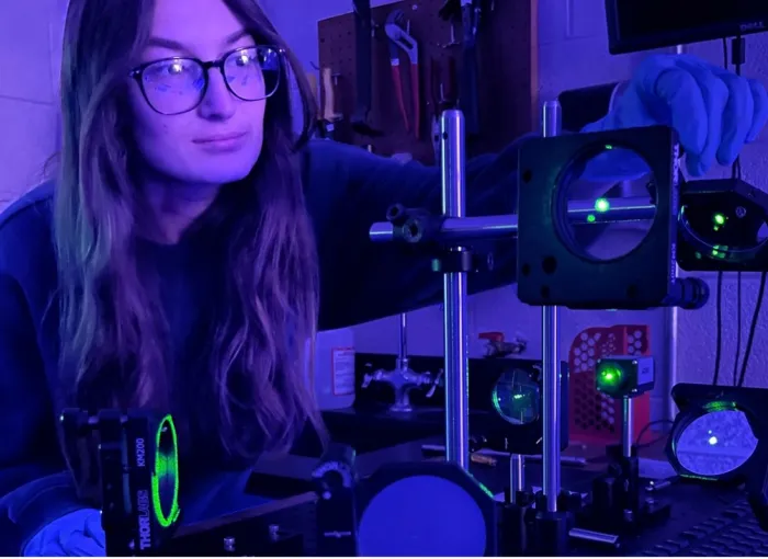 student uses physics equipment in purple lighting