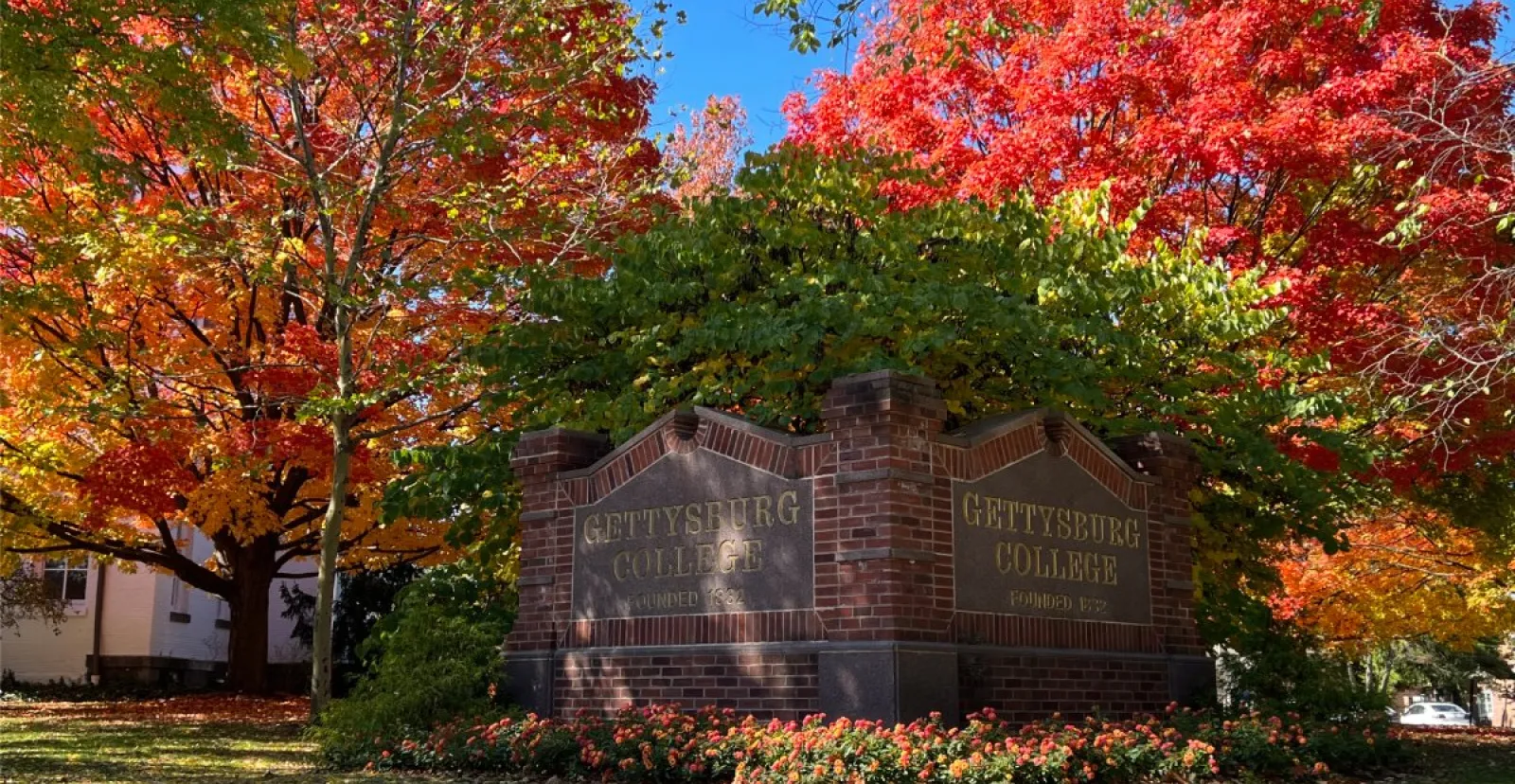 Gettysburg College campus sign with brillian foliage behind it