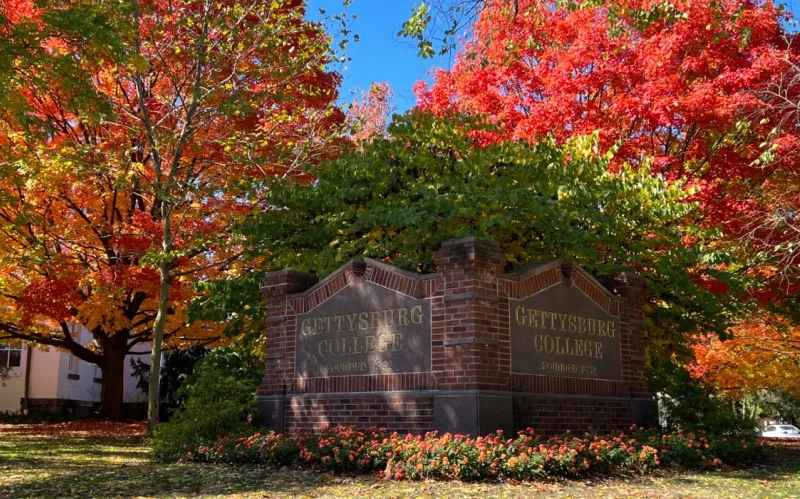 Gettysburg College campus sign with brillian foliage behind it