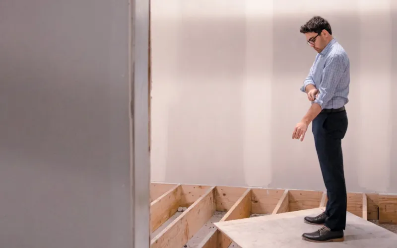 photo of Andrew Dalton standing on plywood looking down into open subfloor