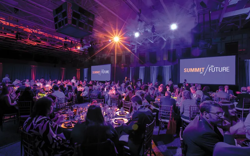 fancy dinner event in purple lighting with summit for the future on screen in background