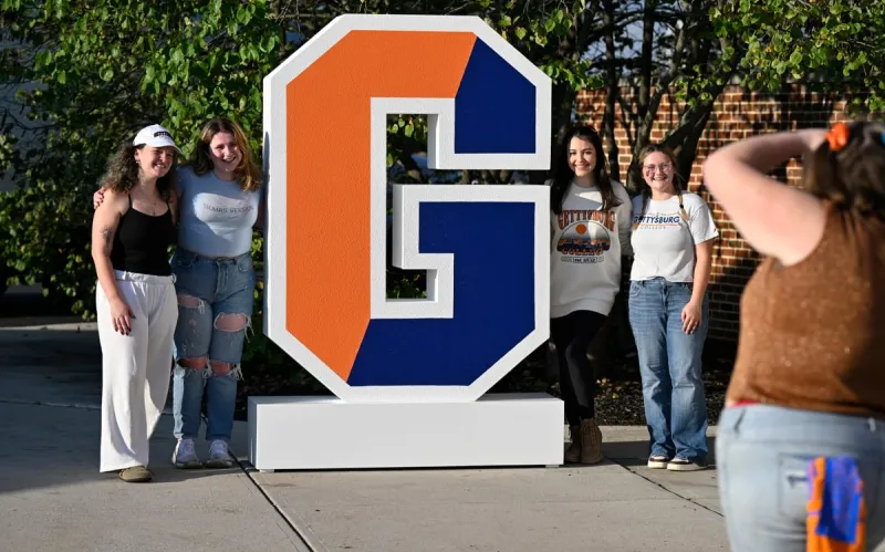 Gettysburg College students pose by the large split G outside the football stadium