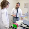 female student and male professor use equipment in lab
